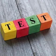 Kolorowe klocki z literami tworzą napis "TEST". Może to być test na neofobię żywieniową, sprawdzający gotowość do próbowania nowych smaków.