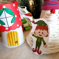 Uroczy elfik obok domku z papieru, jak z bajki. Idealne do stworzenia własnych sanie Mikołaja do druku.