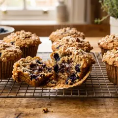 Pyszne muffinki dla niemowlaka z jagodami i czekoladą, posypane płatkami owsianymi, na kratce do studzenia.