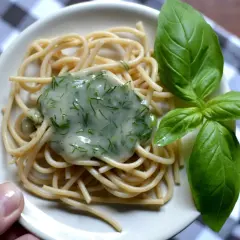 Delikatny makaron spaghetti z kremowym, zielonym sosem koperkowym, idealny jako sos koperkowy dla niemowlaka. Udekorowany świeżymi listkami bazylii.