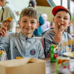 Uśmiechnięci chłopcy jedzą frytki i nuggetsy, świetne pomysły na warsztaty dla dzieci.