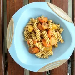 Kolorowy obiad dla dzieci: makaron fusilli z kawałkami marchewki i ziemniaków, doprawiony ziołami.