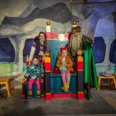 Rodzina w kopalni soli w Wieliczce spotyka króla. Dzieci siedzą na tronach, a mama i król stoją obok.
