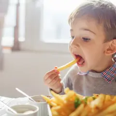 Mały chłopiec z radością zajada się pysznymi frytkami dla dzieci.
