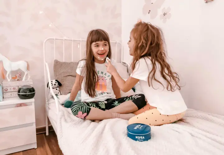 Dwie dziewczynki śmieją się, malując sobie nosy kremem. To świetne kreatywne zabawy dla 8 latka, pełne radości i śmiechu.