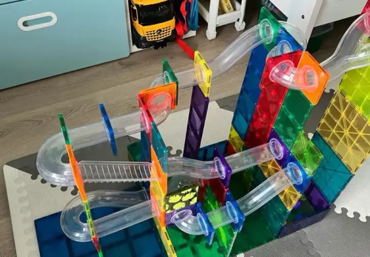 Kolorowe budowle z klocków plastikowych tworzą tor dla kulek. Dziecko bawi się, budując skomplikowane konstrukcje.