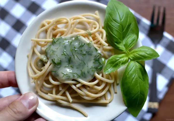 Delikatny makaron spaghetti z kremowym, zielonym sosem koperkowym, idealny jako sos koperkowy dla niemowlaka. Udekorowany świeżymi listkami bazylii.