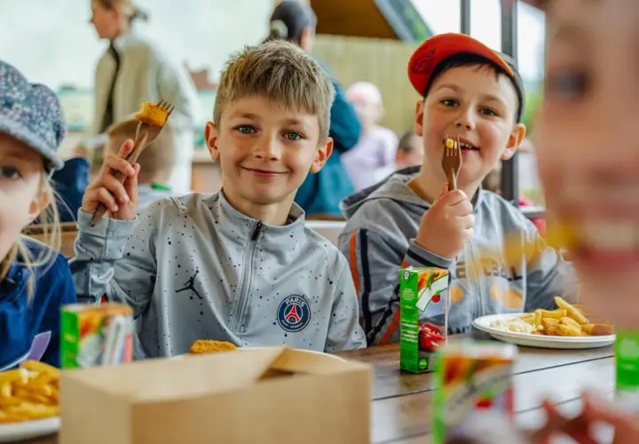 Uśmiechnięci chłopcy jedzą frytki i nuggetsy, świetne pomysły na warsztaty dla dzieci.