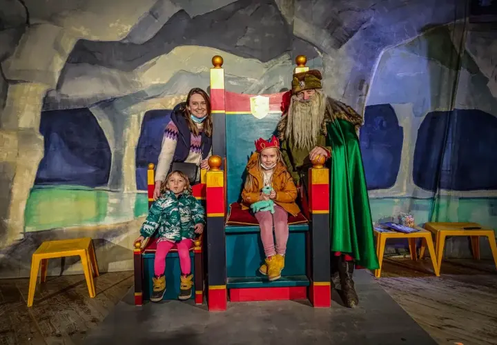 Rodzina w kopalni soli w Wieliczce spotyka króla. Dzieci siedzą na tronach, a mama i król stoją obok.