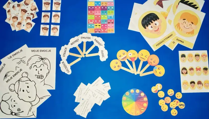 Materiały do zajęć o emocjach: karty z buźkami, plakat, koło emocji i pomoce do opisywania uczuć.