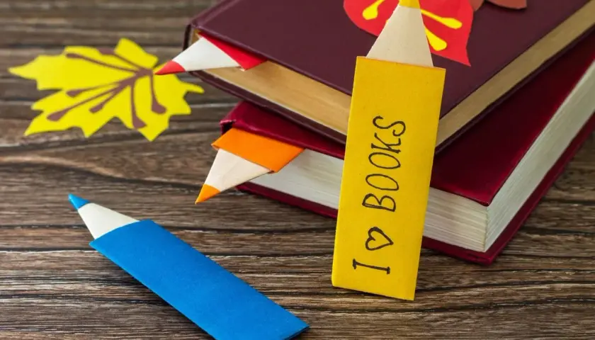 Kolorowe zakładki do książek ręcznie robione przez dzieci, w kształcie kredek. Jedna z nich z napisem "I ♡ BOOKS".