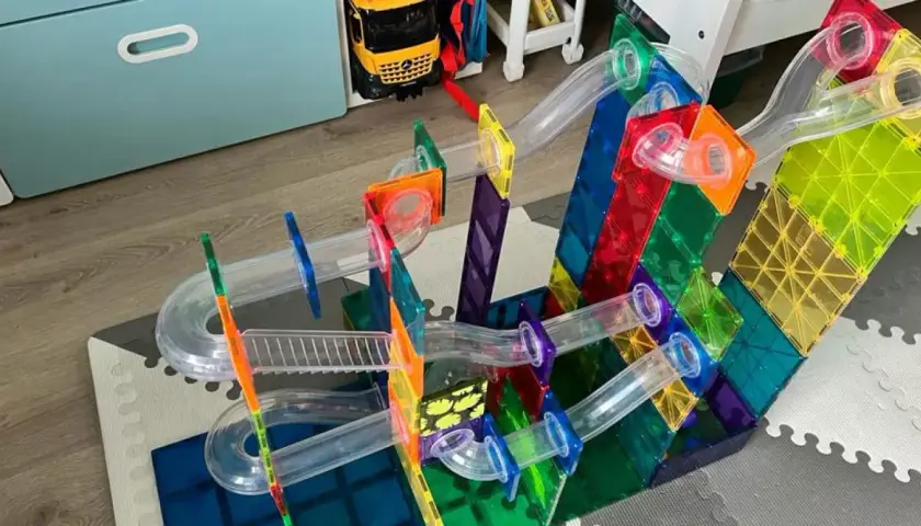 Kolorowe budowle z klocków plastikowych tworzą tor dla kulek. Dziecko bawi się, budując skomplikowane konstrukcje.