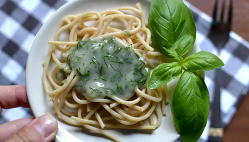 Delikatny makaron spaghetti z kremowym, zielonym sosem koperkowym, idealny jako sos koperkowy dla niemowlaka. Udekorowany świeżymi listkami bazylii.