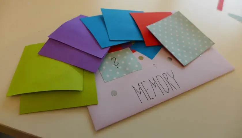 Kolorowe kartki do gry memory do druku, ułożone na kopercie z napisem "MEMORY".