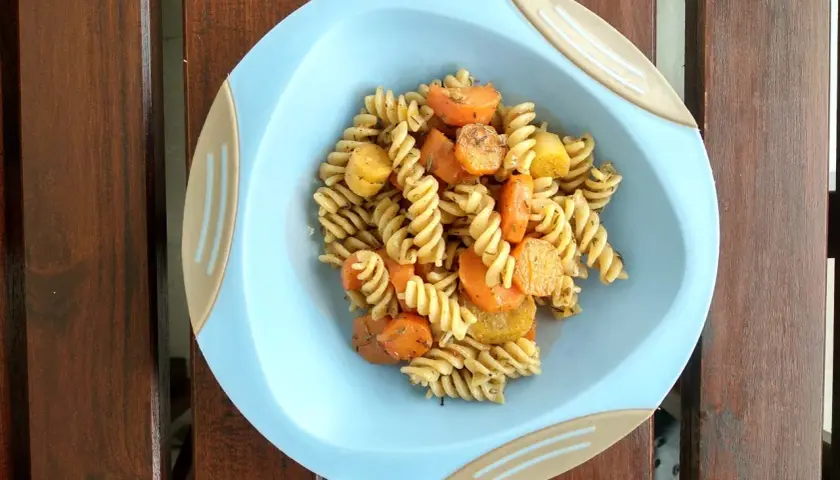 Kolorowy obiad dla dzieci: makaron fusilli z kawałkami marchewki i ziemniaków, doprawiony ziołami.