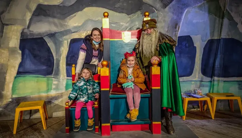 Rodzina w kopalni soli w Wieliczce spotyka króla. Dzieci siedzą na tronach, a mama i król stoją obok.