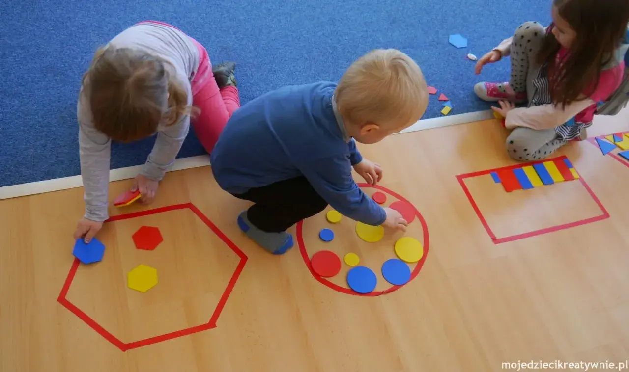 Dzieci układają kolorowe figury geometryczne, tworząc wzory w wyznaczonych obszarach.