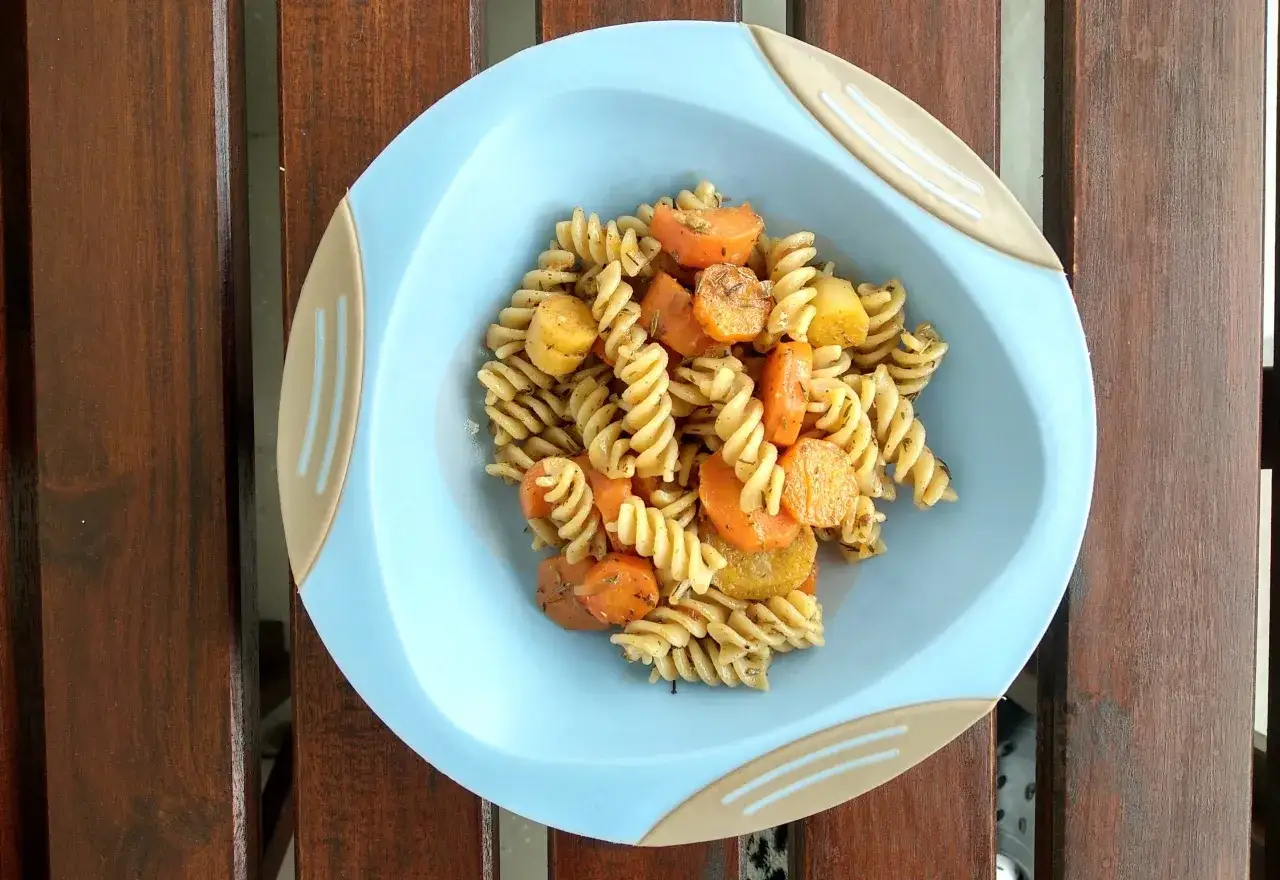 Kolorowy obiad dla dzieci: makaron fusilli z kawałkami marchewki i ziemniak&oacute;w, przyprawiony ziołami.
